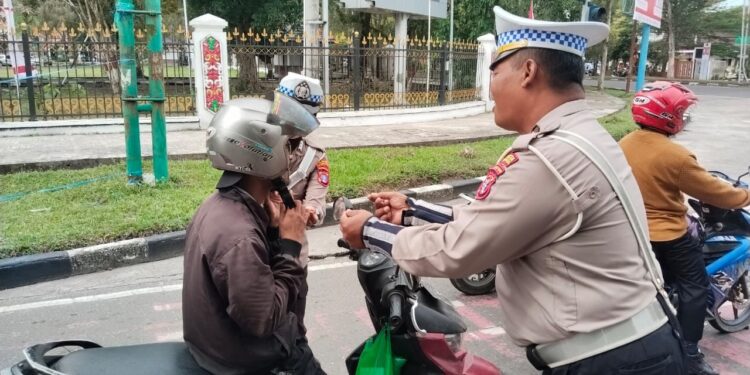 FOTO: MATAKALTENG - Personel Satlantas Polresta Palangka Raya, pada saat meminta warga untuk memasang helmnya dengan benar.