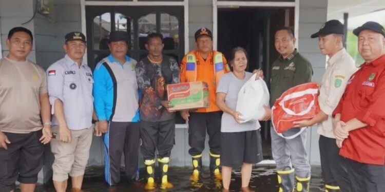 Foto : Bupati Sukamara, Masduki saat menyerahkan bantaun kepada korban banjir di Kecamatan Sukamara akibat naiknya debit Sungai Jelai.