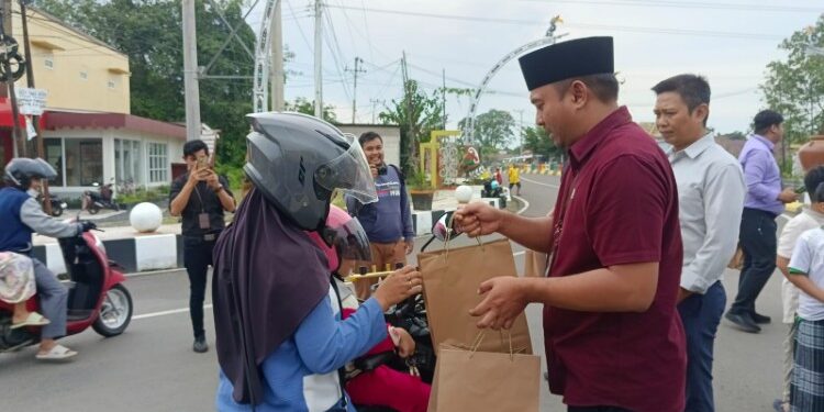 FOTO : Kepala Bank Kalteng Cabang Pulang Pisau, Ferry Yanto saat membagikan paket takjil kepada salah seorang pengendara sepeda motor.
