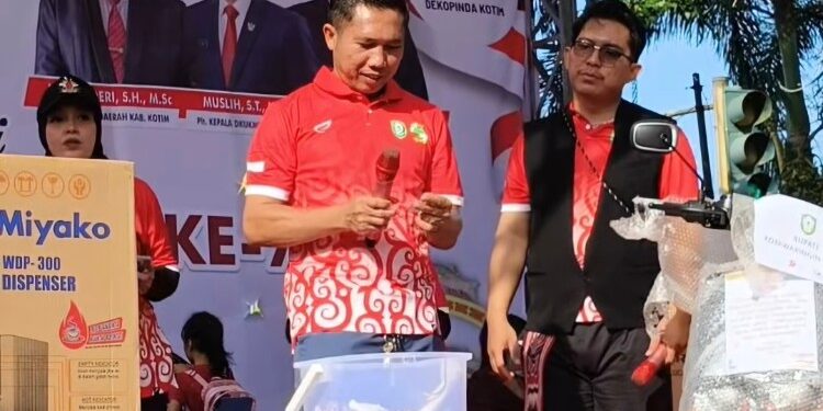 Foto:IST/MATA KALTENG - Plt. Kepala Dinas Koperasi, UKM, Perindustrian dan Perdagangan (DKUKMPP) Kotim sekaligus Ketua Panitia, Muslih saat undi kupon jalan sehat.